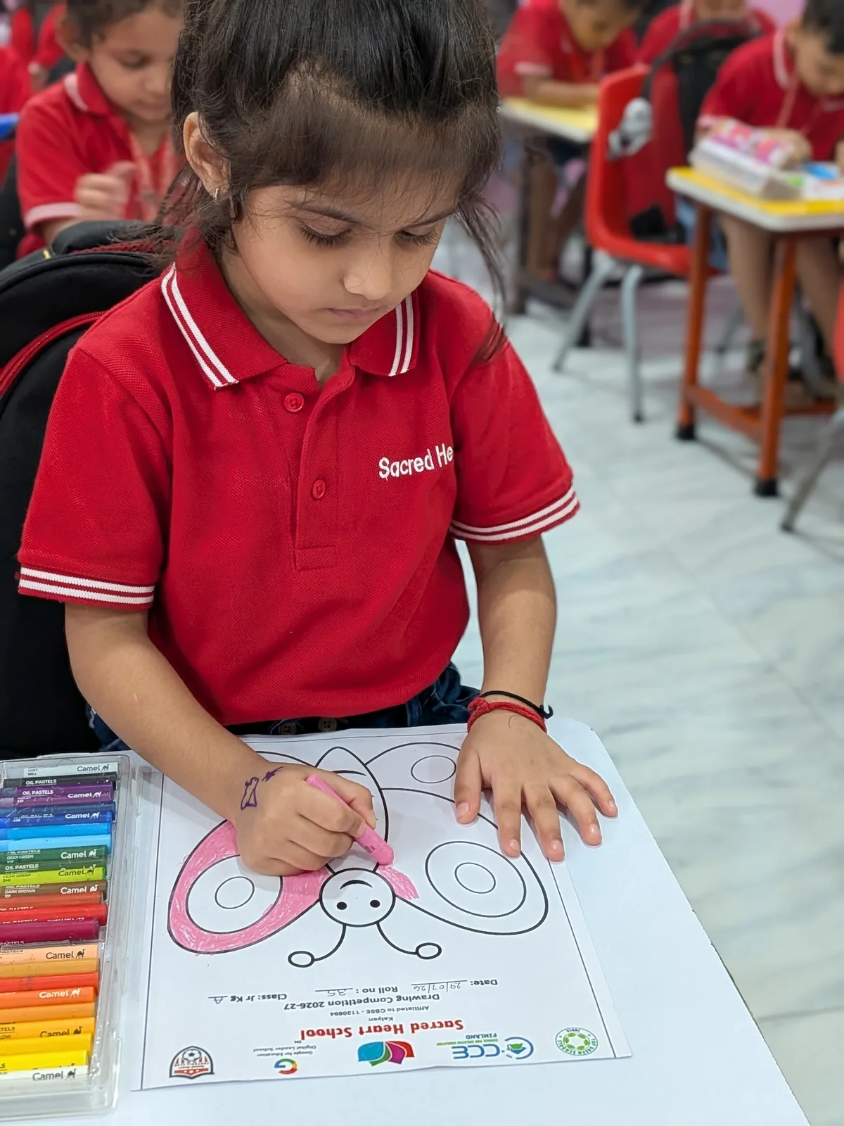 A Pre-Primary child colouring a butterfly worksheet