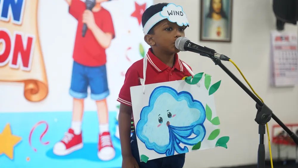 A Pre-Primary child reciting with a cloud-shaped prop at the Recitation Competition