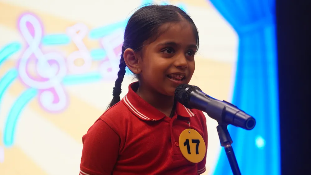 A Pre-Primary child singing on stage at the Singing Competition