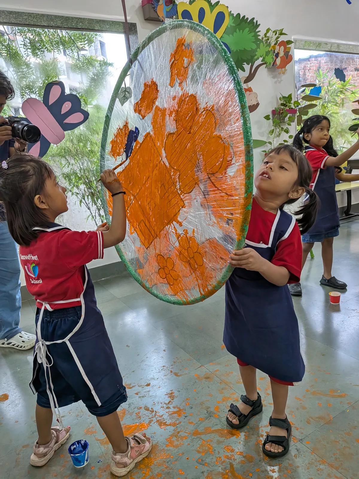 Children painting a large hoop with orange paint