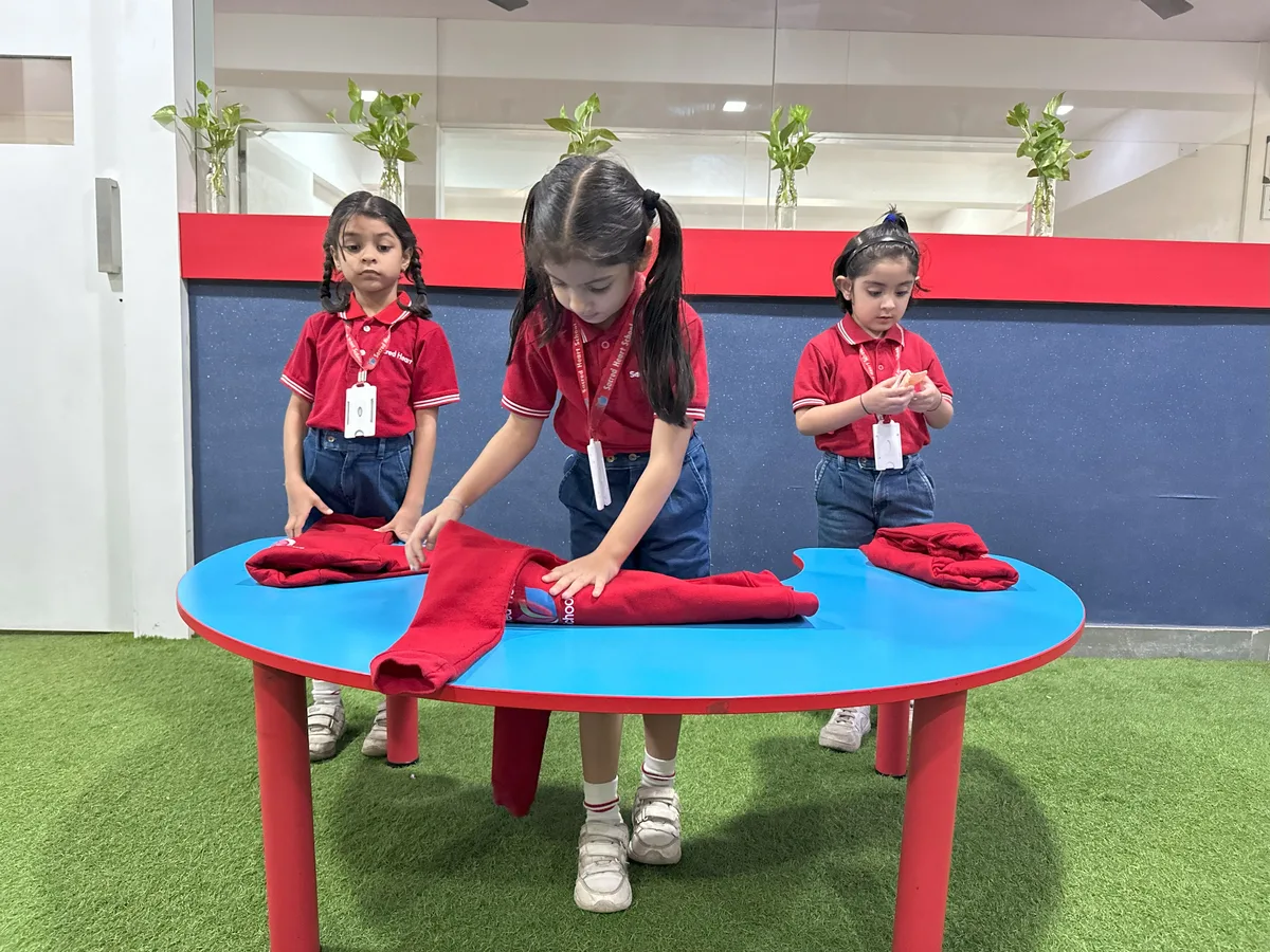 Children folding cloth napkins at a round table