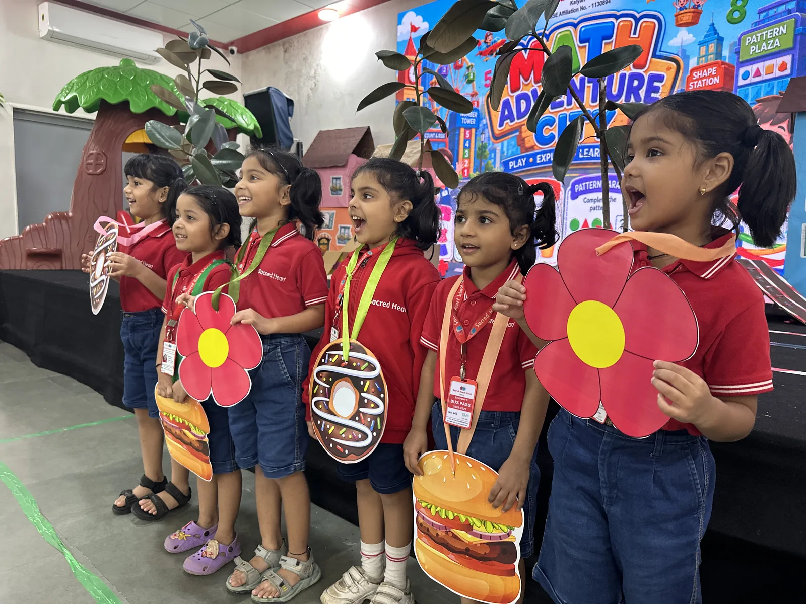 Pre-Primary children holding flower-shaped name tags in class