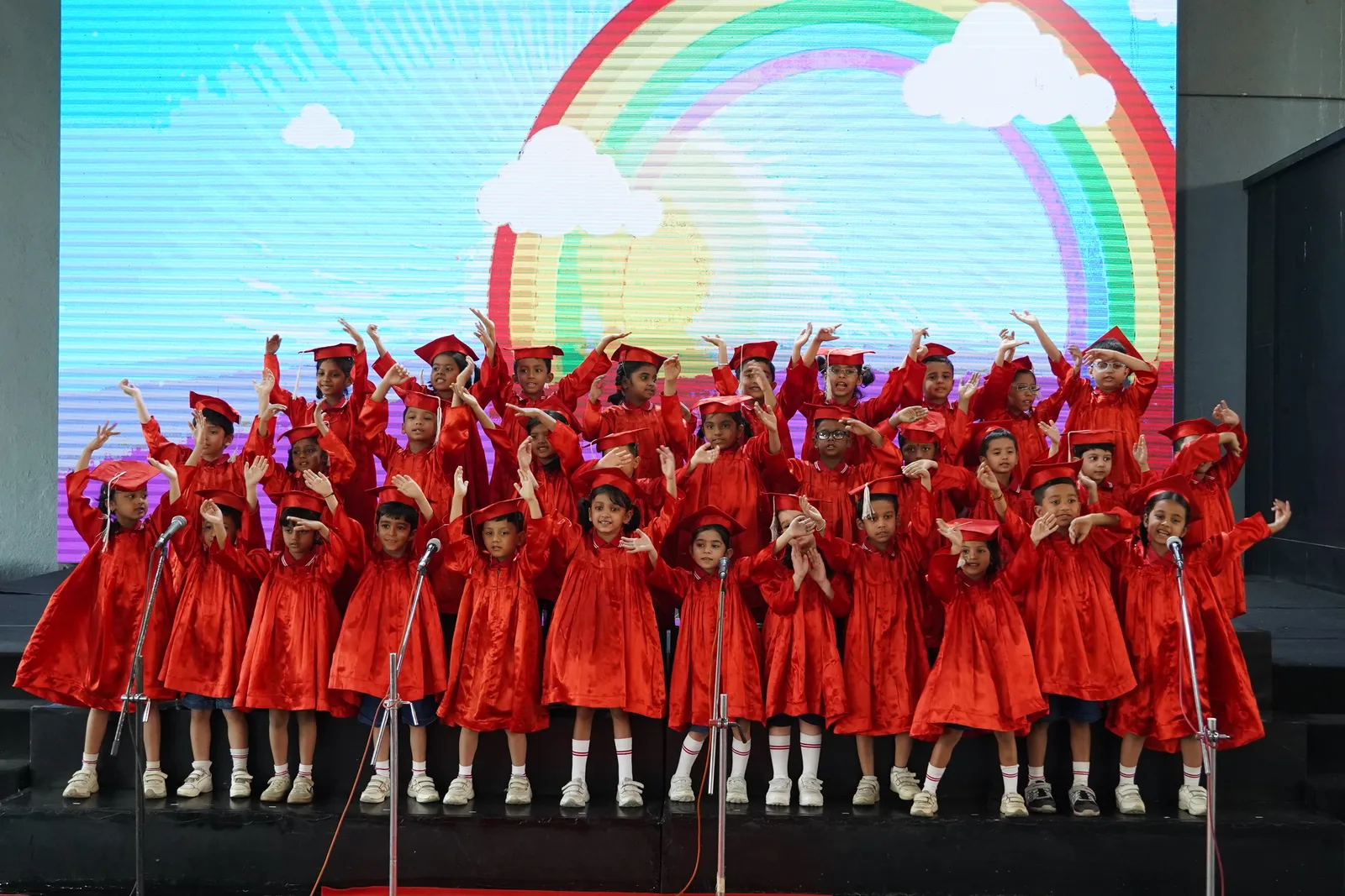 Pre-Primary children performing on stage under a rainbow backdrop