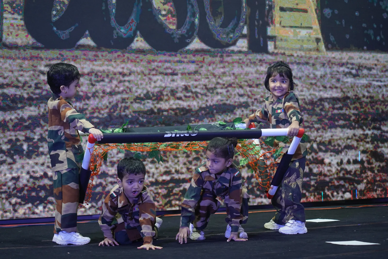 Children in army costumes carrying a stretcher in a patriotic performance