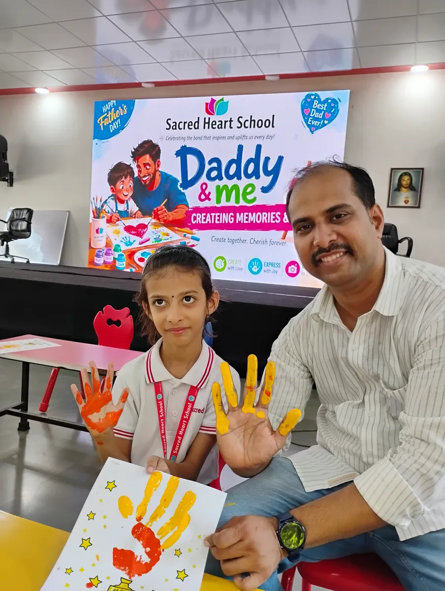 A father and daughter showing their handprint art at the Daddy & Me event