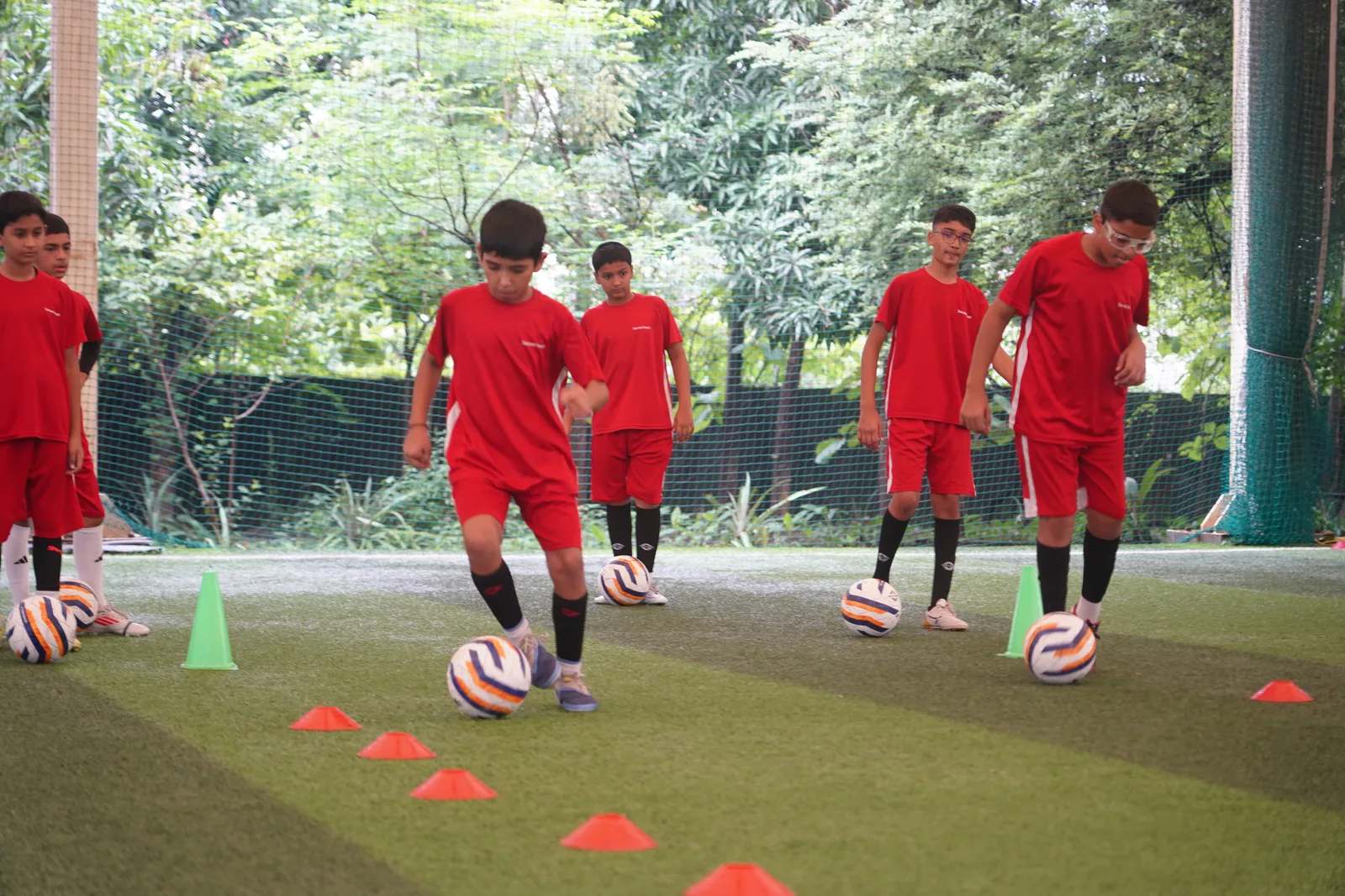 Students dribbling through cones during football drills