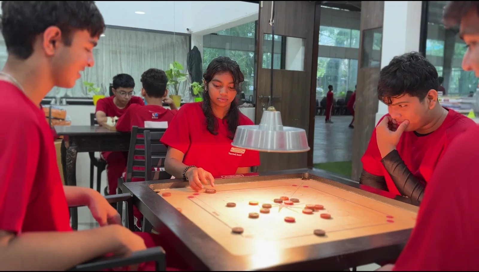 A coach guiding a student during a carrom match